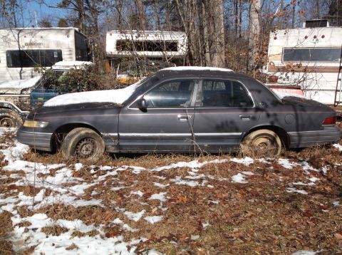 1974 Dodge Challenger - A dark gray sedan sits in a wooded area with patches of snow on the ground and on the vehicle's roof. The car appears to be abandoned, with…