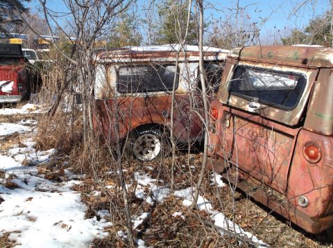 1974 Dodge Challenger - Two rusty, abandoned vintage vans are partially obscured by bare branches and snow. The van on the left has a visible Goodyear tire and the…