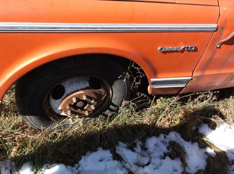 1974 Dodge Challenger - The right rear wheel and fender of an orange vehicle are shown, with a chrome trim piece above the wheel well and a "Custom 10" emblem on t…