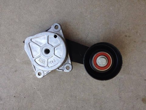 1998 Ford Crown Victoria - Aluminum automatic belt tensioner assembly with its idler pulley, laid on a concrete floor.