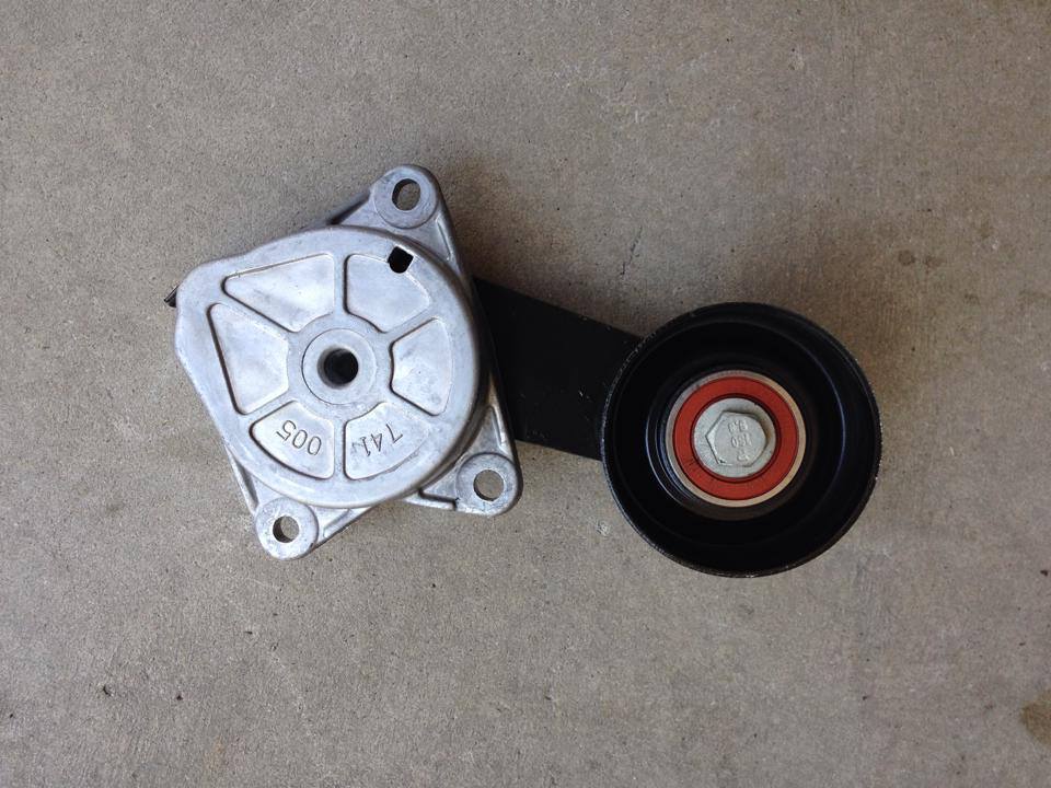 Aluminum serpentine belt tensioner assembly with idler pulley on concrete