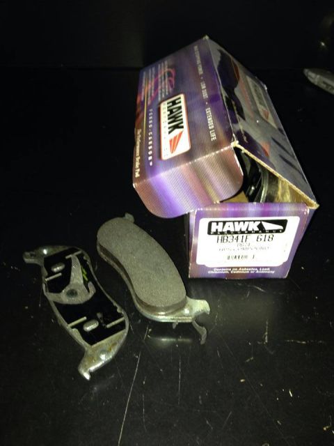 1998 Ford Crown Victoria - set of Hawk brake pads next to their purple retail box labeled 'HB341F.618' on a dark surface.