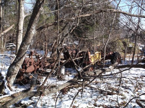 1974 Dodge Challenger - Two rusty, abandoned tractors are partially visible in a wooded area covered in snow. One tractor has a yellow tarp draped over it.