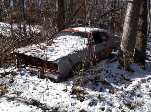 1974 Dodge Challenger - An abandoned 1974 Dodge Challenger is covered in snow and surrounded by trees and branches. The car appears to be rusting and in a state of…