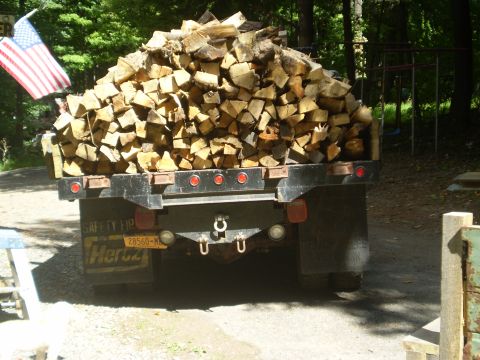 1979 Ford Bronco - The rear of a trailer loaded with firewood is shown, with an American flag waving in the background. The trailer has a New York license pla…