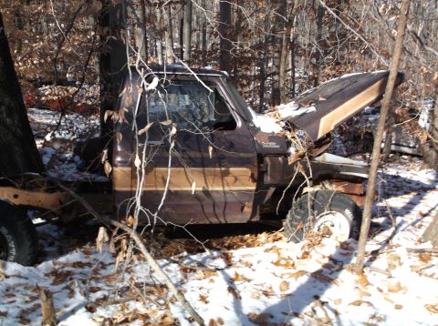 1974 Dodge Challenger - A weathered, brown and tan pickup truck is partially submerged in snow and surrounded by trees and fallen leaves. The hood is open, reveali…
