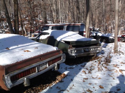1974 Dodge Challenger - Abandoned vehicles sit under a blanket of snow in a wooded area, suggesting a long period of disuse.