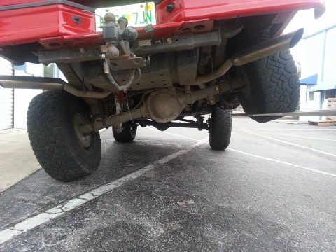 1995 Ford Bronco - Underside view of a red 1995 Ford Bronco, showing the rear axle and suspension components.