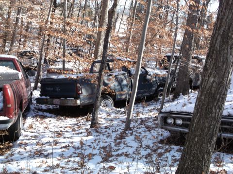 1974 Dodge Challenger - Multiple vehicles are seen in a snowy junkyard, with one car's front end visible, suggesting a 1970s model.