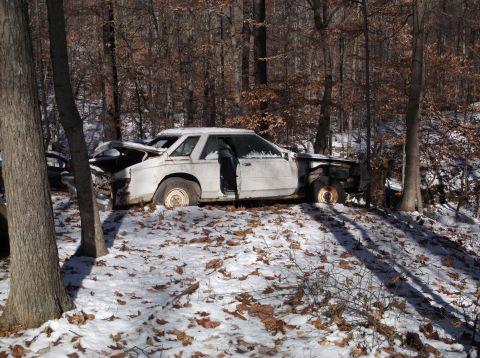 1974 Dodge Challenger - Abandoned white car in a snowy forest setting, showing significant front-end damage.