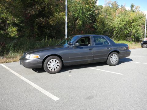 2001 Ford Crown Victoria - A dark gray 2001 Ford Crown Victoria is parked in a lot on a sunny day.