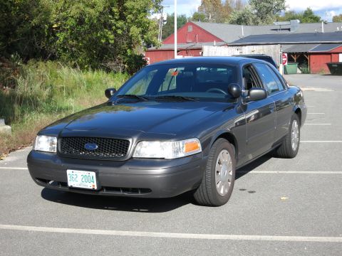 2001 Ford Crown Victoria - This dark grey sedan is seen parked in a lot. The license plate is visible and reads 362 2004.