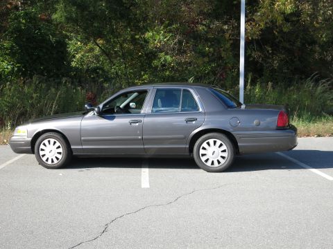 2001 Ford Crown Victoria - Side profile of a gray 2001 Ford Crown Victoria sedan parked outdoors.