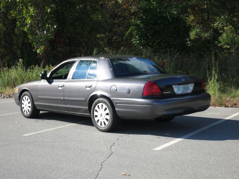 2001 Ford Crown Victoria - A grey 2001 Ford Crown Victoria is parked in a lot, viewed from the rear three-quarter angle. The license plate reads 662-200A.