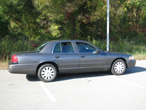2001 Ford Crown Victoria - Side profile of a grey 2001 Ford Crown Victoria sedan parked in a lot.