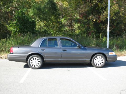 2001 Ford Crown Victoria - A gray 2001 Ford Crown Victoria is parked outside with trees in the background.