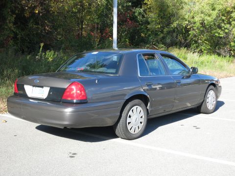2001 Ford Crown Victoria - Rear view of a 2001 Ford Crown Victoria sedan parked in a lot with trees in the background.