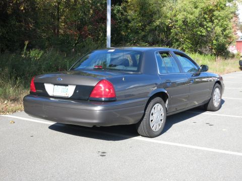 2001 Ford Crown Victoria - This sedan is parked in a lot with trees in the background. The license plate indicates it is a 2004 model.