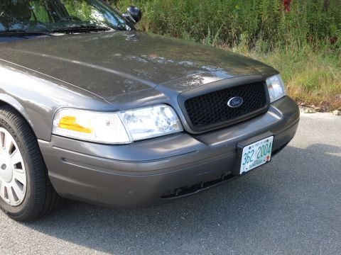 2001 Ford Crown Victoria - The front of a gray Ford Crown Victoria shows its grille and headlights, with a license plate dated 2004.