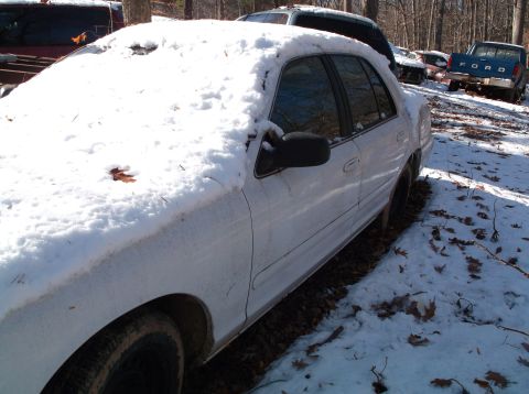 1974 Dodge Challenger - A white sedan sits covered in snow in a yard with other vehicles around.