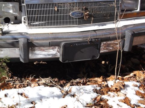 1974 Dodge Challenger - The front of a weathered Ford vehicle is visible, with a license plate and grille showing signs of age.