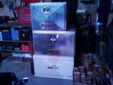 1973 Ford F-250 - Stacked toolboxes are stored in a workshop setting with shelves and tools in the background.