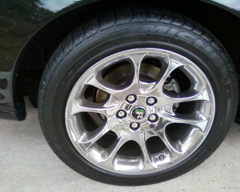 1998 Ford Crown Victoria - Close-up of a chrome wheel with a green and black emblem on a tire.