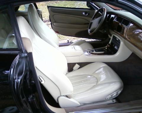 1998 Ford Crown Victoria - The interior of a Jaguar XK shows cream leather seats and a wood-trimmed dashboard.