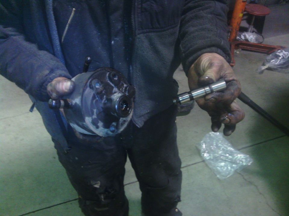Person holding a greasy automotive pump assembly and a cylindrical part.
