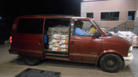 2000 Chevrolet Astro - A maroon Chevrolet Astro van is packed full of stacks of newspapers or magazines. A person is sitting in the driver's seat, looking at pape…