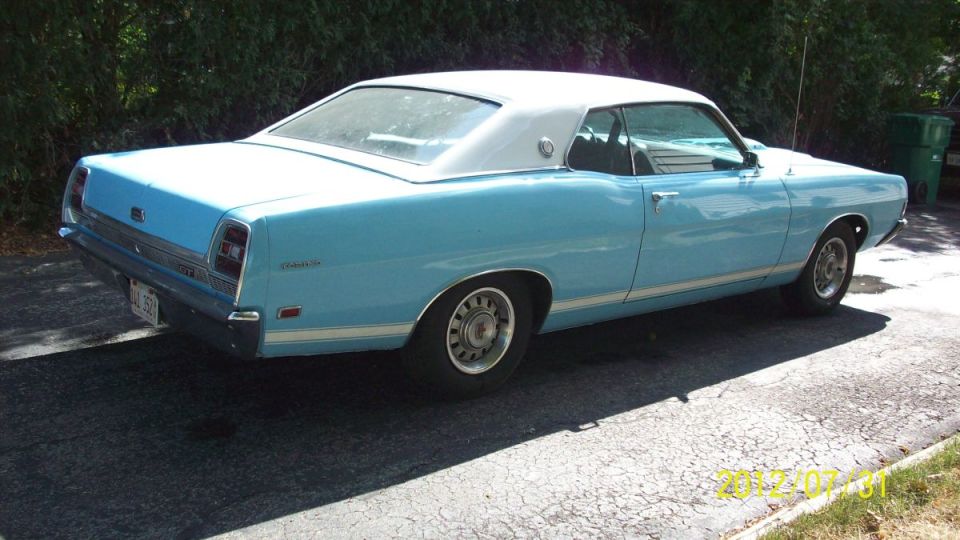 1969 Ford Torino coupe, rear passenger side view, light blue with white vinyl roof.