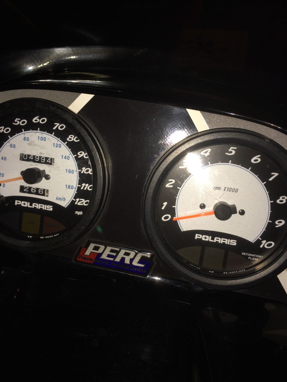 Polaris snowmobile instrument cluster with speedometer reading 04994 and tachometer, PERC sticker