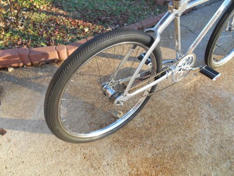 Close-up of a custom bicycle's rear wheel, chain, and chrome frame.