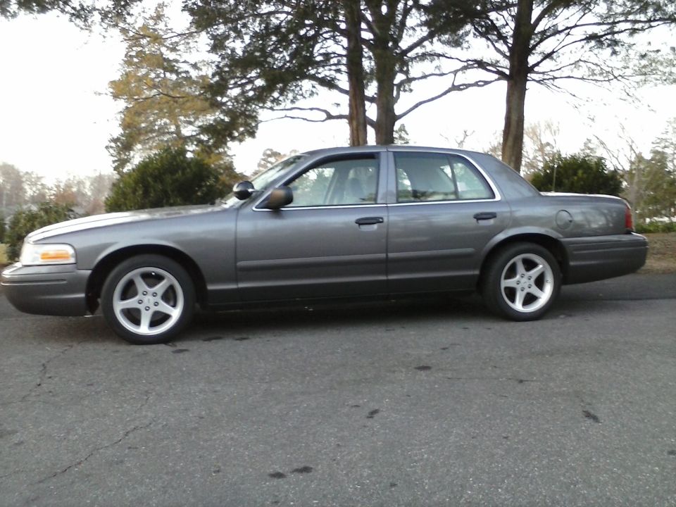 Gray 2006 Ford Crown Victoria parked on asphalt road, side view.