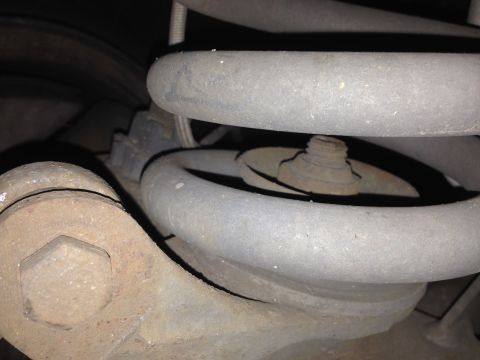 1992 Ford F-150 - This is a close-up view of the suspension system of a vehicle, focusing on a coil spring and a bolt. The components appear to be made of me…