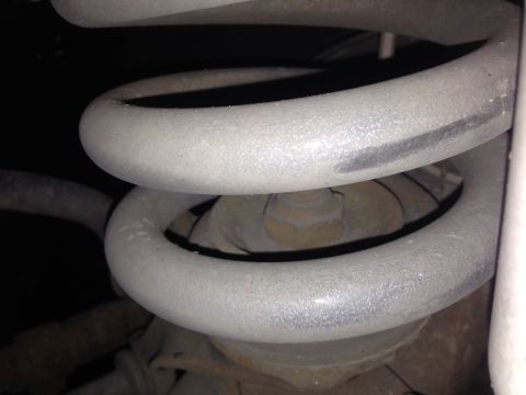 1992 Ford F-150 - A close-up view of the suspension system of a 1992 Ford F-150, focusing on the coil spring and surrounding components. The coil spring is p…