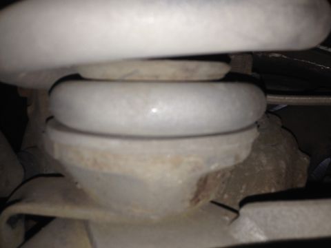 1992 Ford F-150 - A close-up, low-angle shot shows the top of a white coil spring resting on a metal mount. The spring appears to be part of a vehicle's susp…