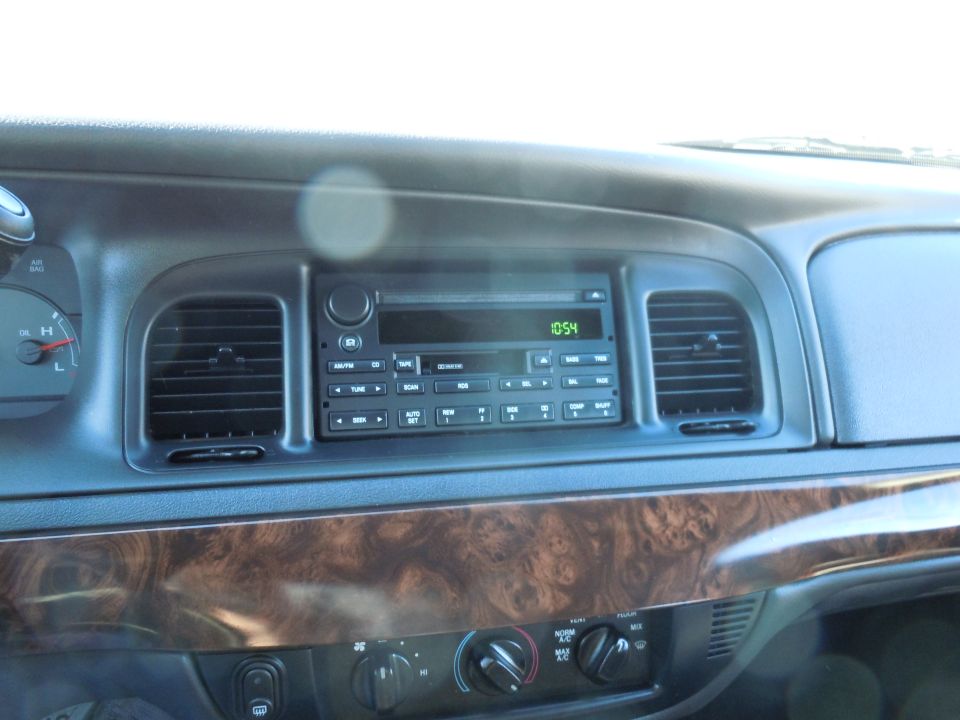 2001 Ford Crown Victoria dashboard with radio, climate controls, wood trim, and oil gauge.