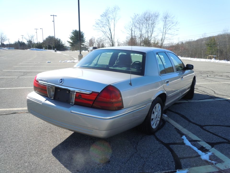 Silver 4-door sedan, rear 3/4 view, parked in an asphalt lot.