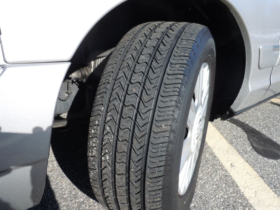 Silver sedan front passenger tire and wheel well