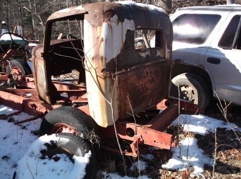 1974 Dodge Challenger - A heavily rusted and partially dismantled vintage truck cab sits in a snowy outdoor setting next to a modern white SUV.