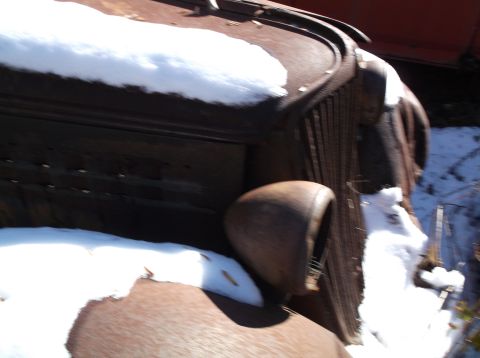1974 Dodge Challenger - A close-up view of a rusty car's front end, partially covered in snow.