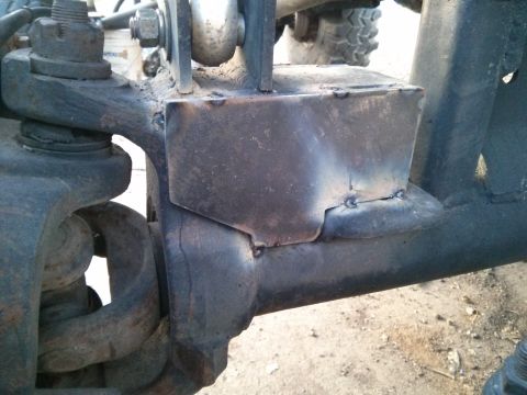 1986 Ford Bronco - A close-up view of a welded metal bracket attached to the suspension components of a vehicle. The bracket appears to be a custom modificati…