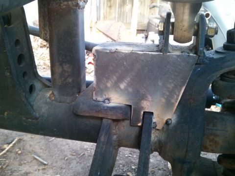 1986 Ford Bronco - This close-up photo shows a custom-fabricated metal bracket welded onto the frame of a vehicle, likely part of a suspension modification. T…