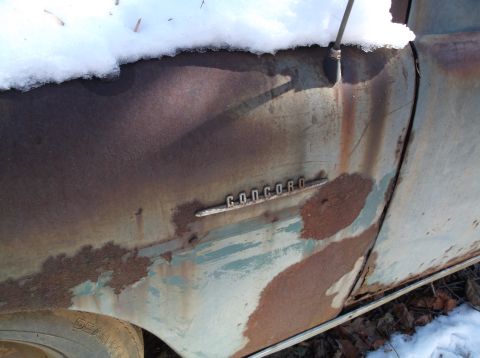 1974 Dodge Challenger - A close-up view of the rusted fender and door of an old vehicle, with the word "CONCORD" visible on a chrome emblem. Snow covers the top ed…