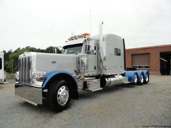 Silver Peterbilt 379 semi-truck with blue fenders and chrome details, parked outdoors.