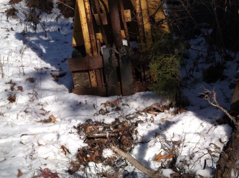 1974 Dodge Challenger - A close-up view of the front of a rusty yellow industrial machine, possibly a forklift, partially covered in snow and fallen leaves. The ma…