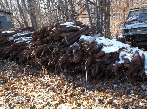 1974 Dodge Challenger - A large pile of rusty, cylindrical metal parts, possibly exhaust components, are stacked in an outdoor setting with scattered snow and fall…