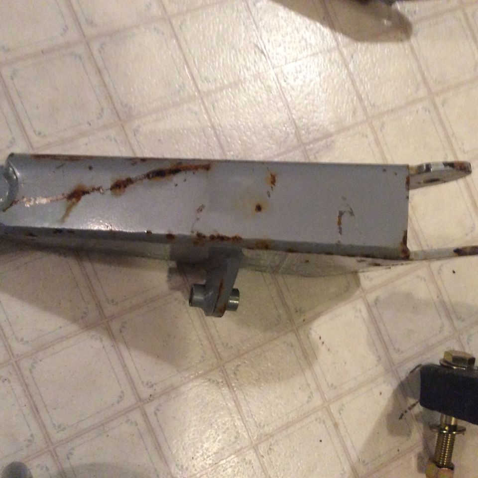 Gray metal part with rust spots on a tiled floor.