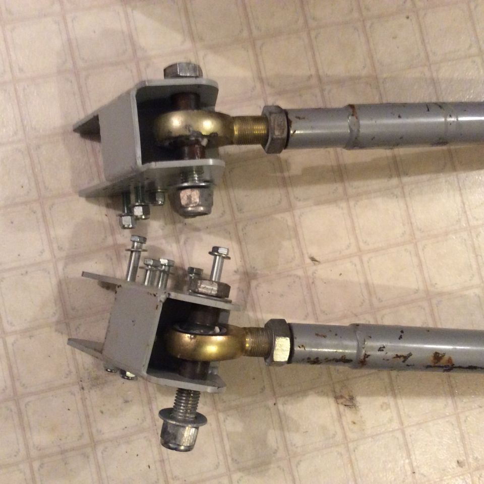Two gray adjustable control arms with gold spherical bearings and mounting brackets.
